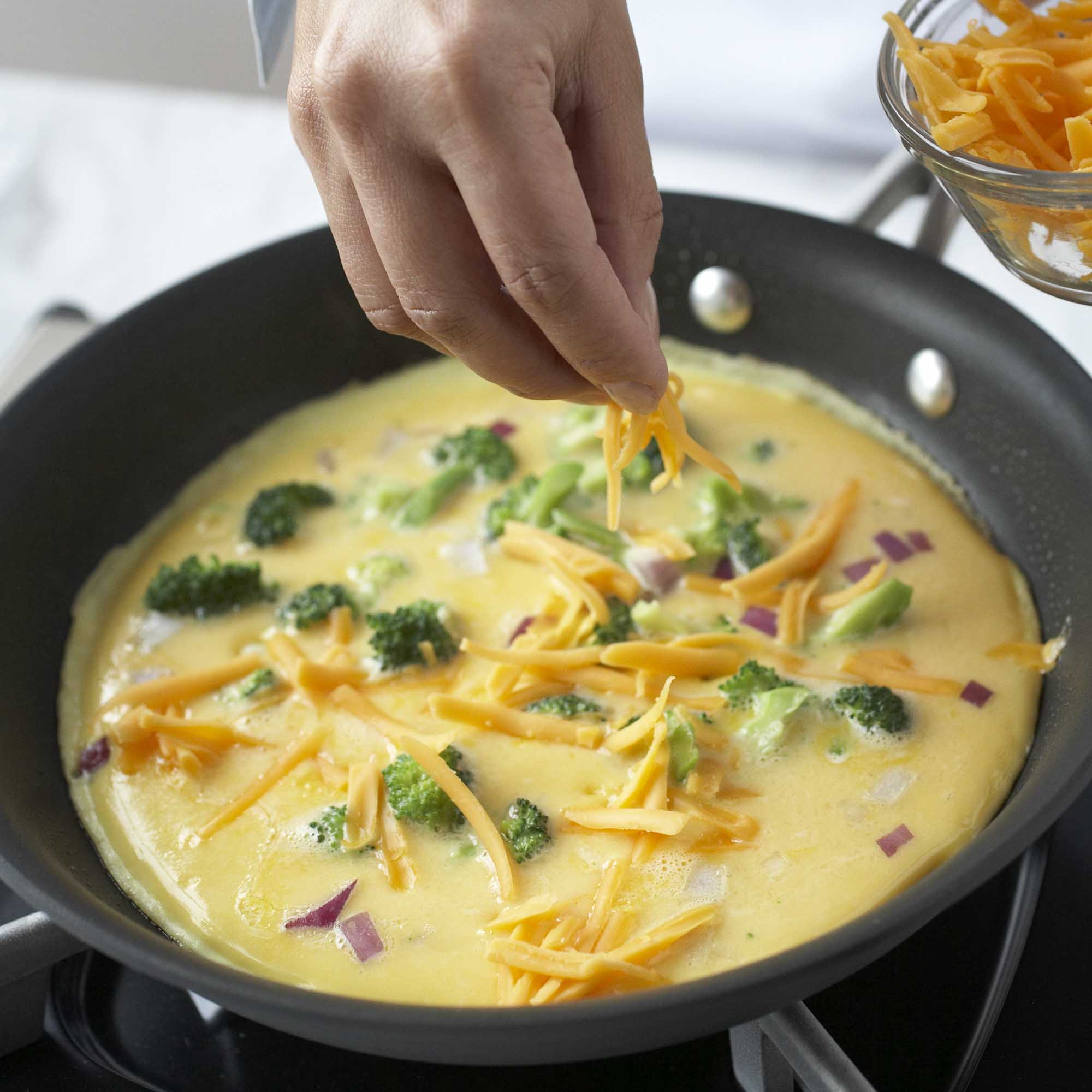 adding toppings to a frittata in a pan