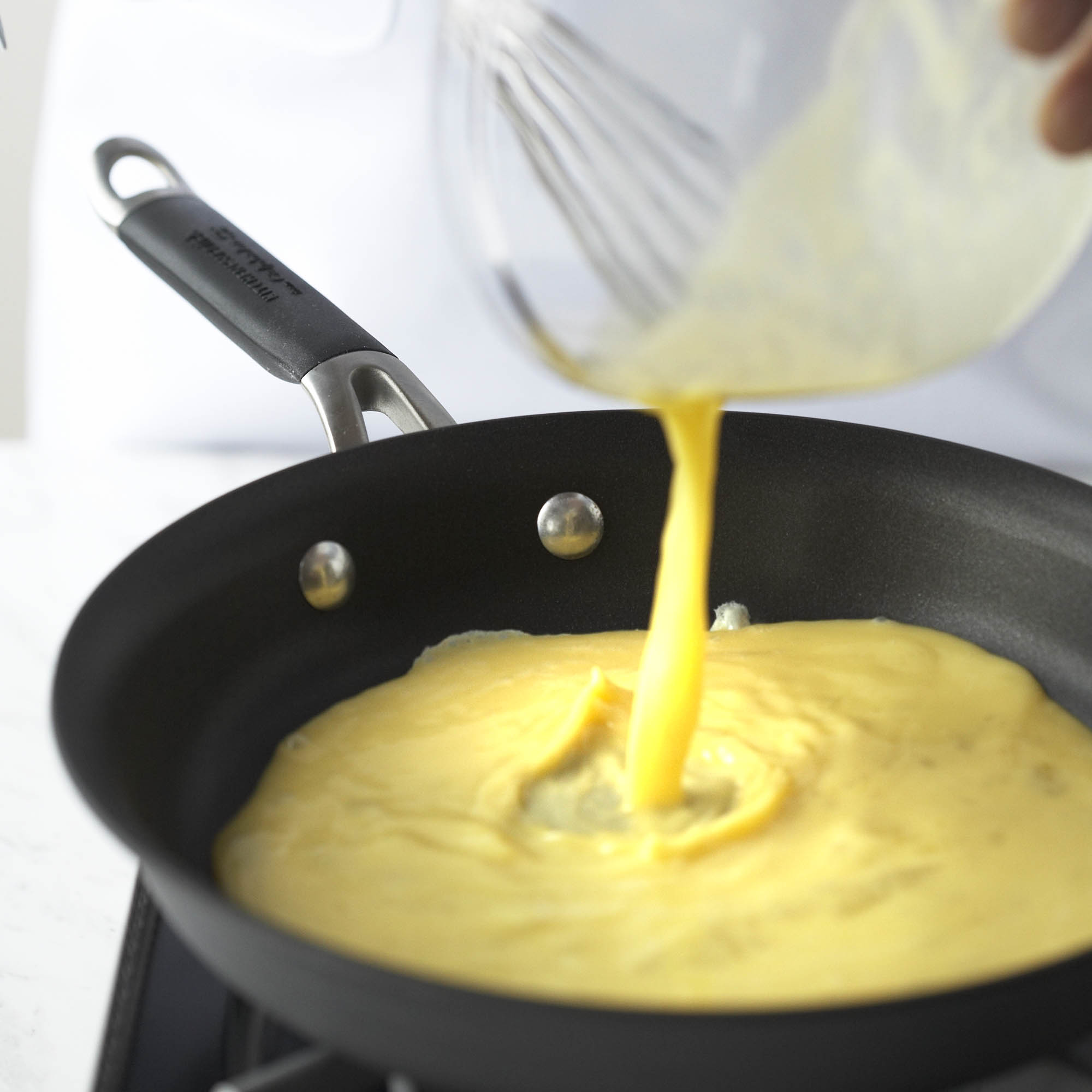 pouring eggs into a pan