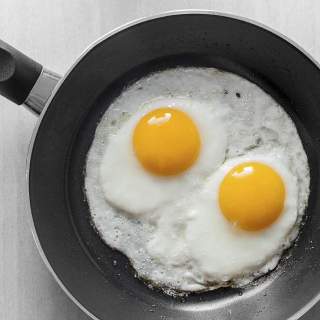 two eggs frying in a pan