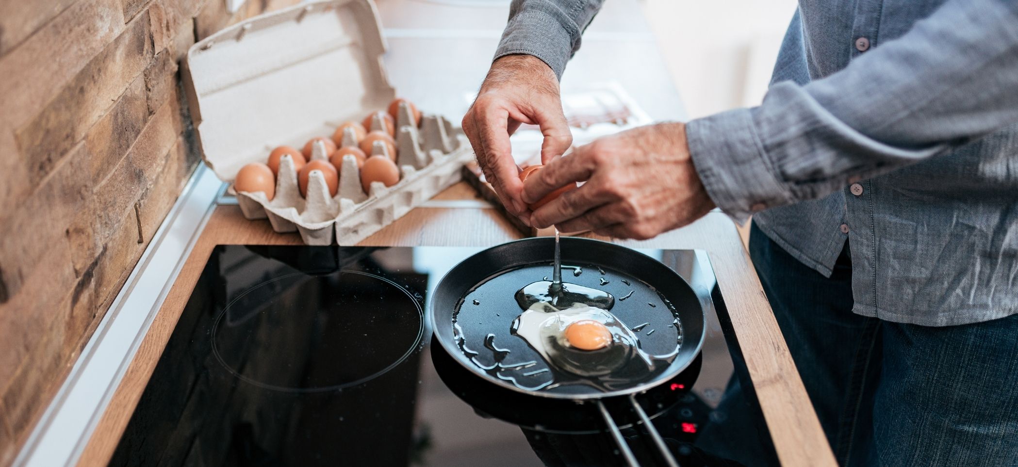 a man cracks an egg into a hot pan