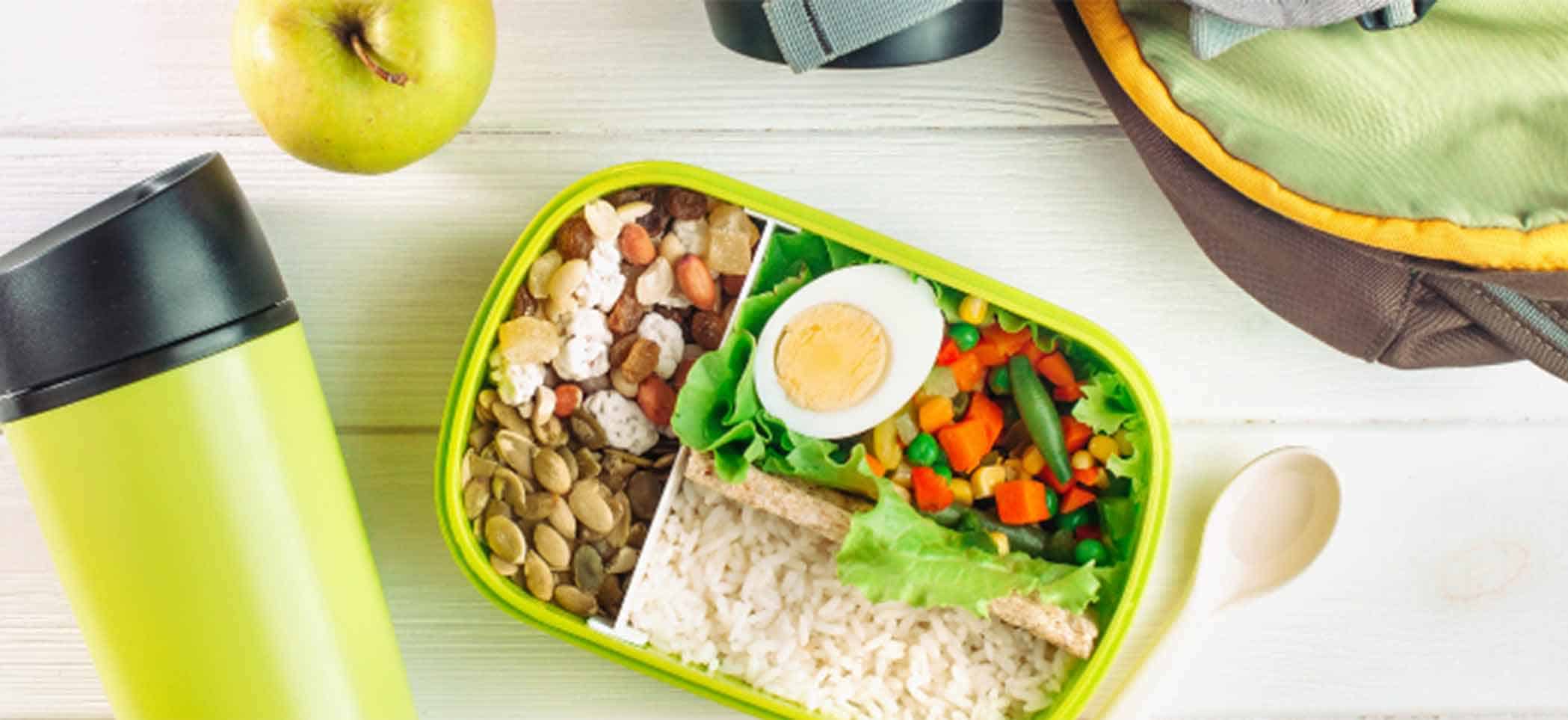 a lunchbox that holds nuts, rice, salad, and hard-boiled egg
