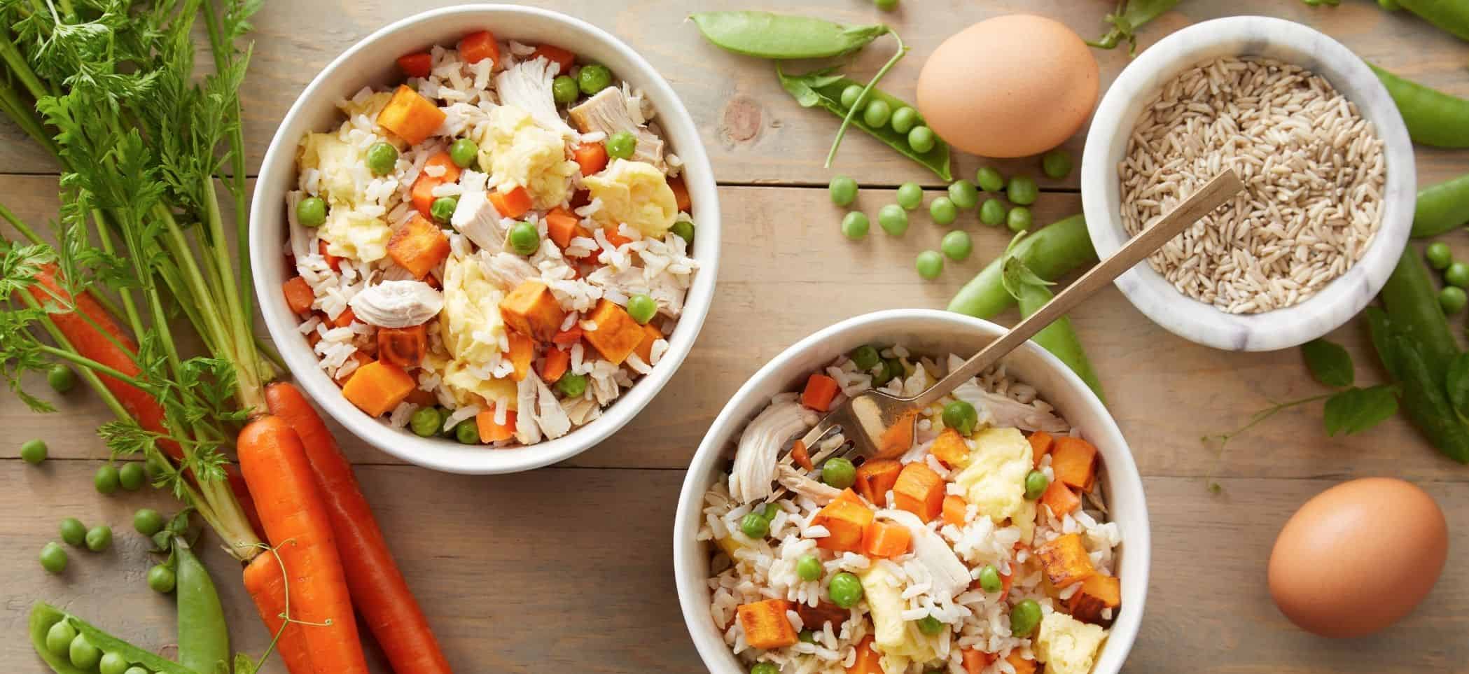 a bowl of rice, chicken, egg, carrot, and peas