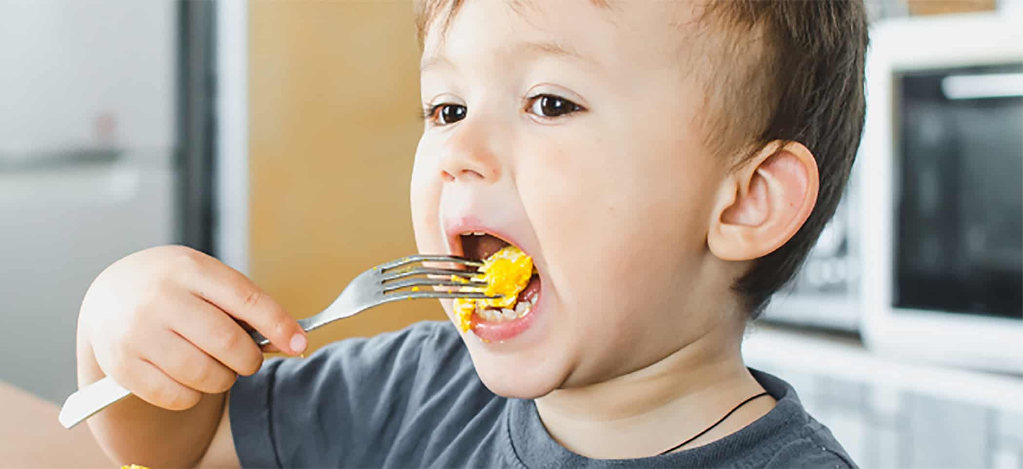 a child puts a forkful of food in his mouth