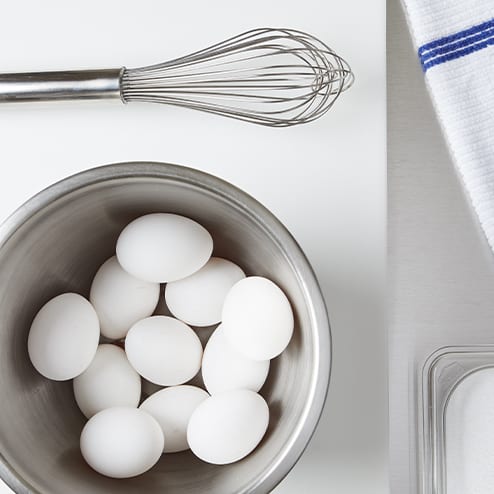 eggs in a bowl next to a whisk
