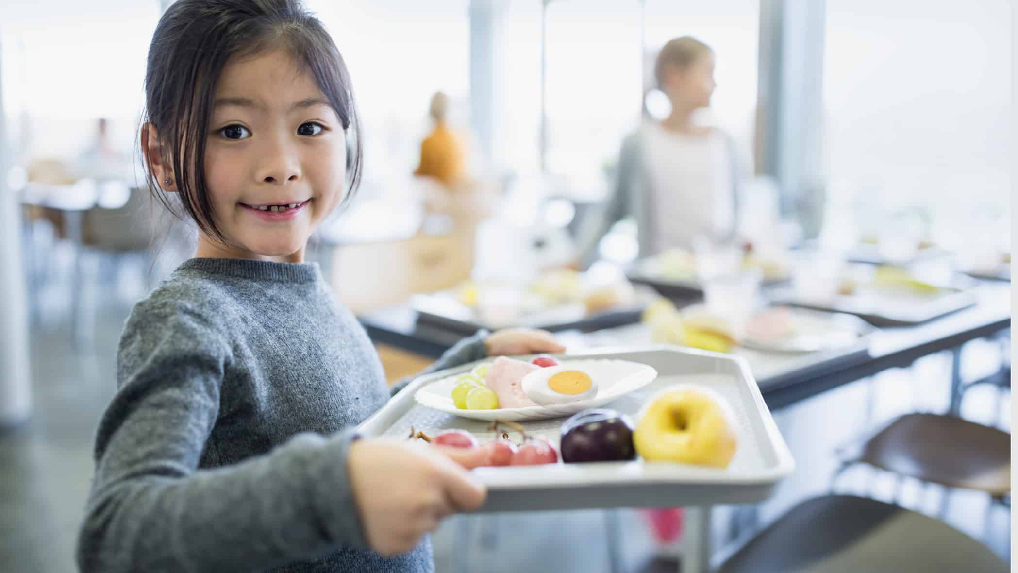 a young girl with a school lunch tray