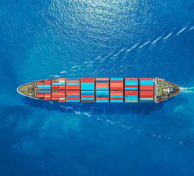 an overhead shot of a ship full of shipping containers sailing on the ocean