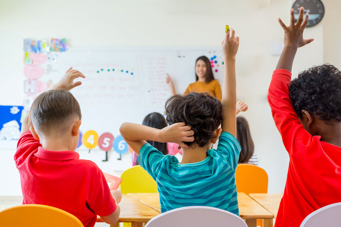 a classroom of children raise their hands