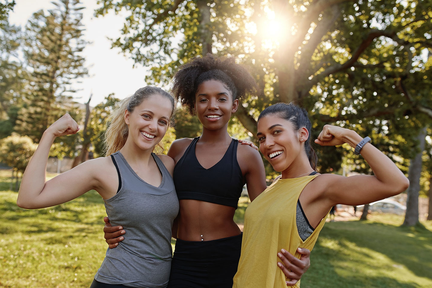 three women wearing athletic clothing in a park