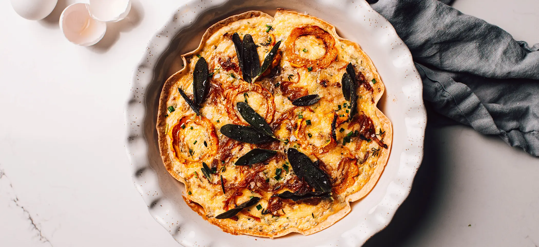 Tortilla Crust Winter Quiche with Delicate Squash, Feta, Caramelized Onions, Hot Honey, and Fried Sage