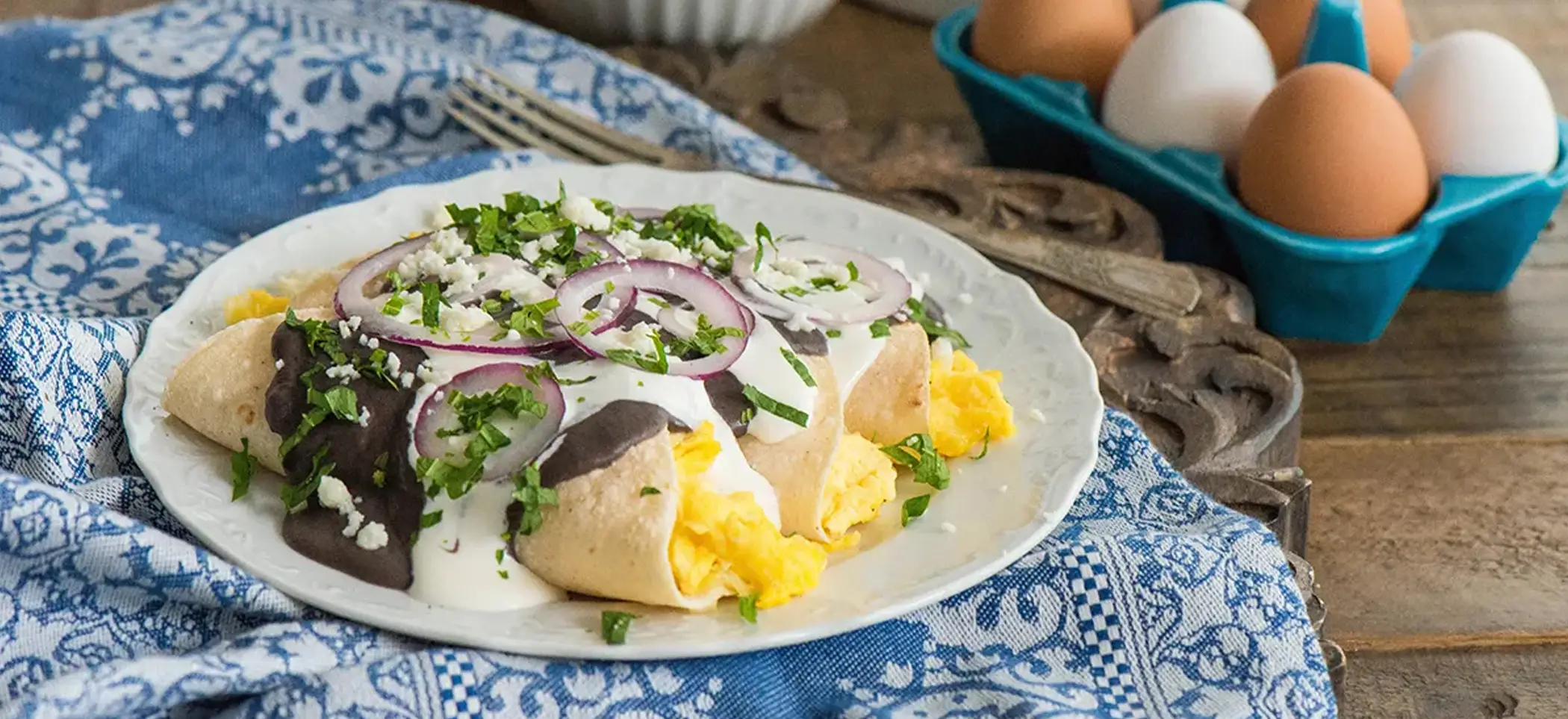 Platillo de huevos veracruzanos junto a seis huevos y bol de queso fresco