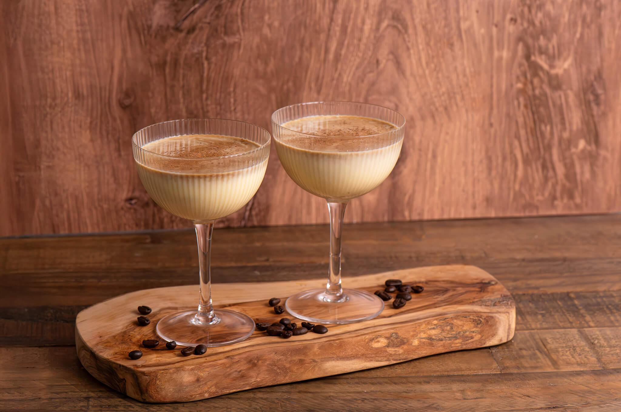 Two glasses of Espresso Elevation Eggnog on top of a wooden board